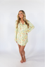A woman smiling, wearing a green sleep dress with a floral wildflowers pattern.