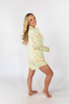 A woman smiling, wearing a green sleep dress with a floral wildflowers pattern.