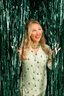 Woman in a green patterned pajama set standing in front of a green tinsel curtain