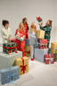 Five women surrounded by Christmas presents in a studio setting
