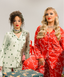 Two women in festive pajamas with wrapped presents on a neutral background