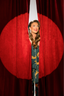 Woman peeking through a red curtain with a spotlight effect